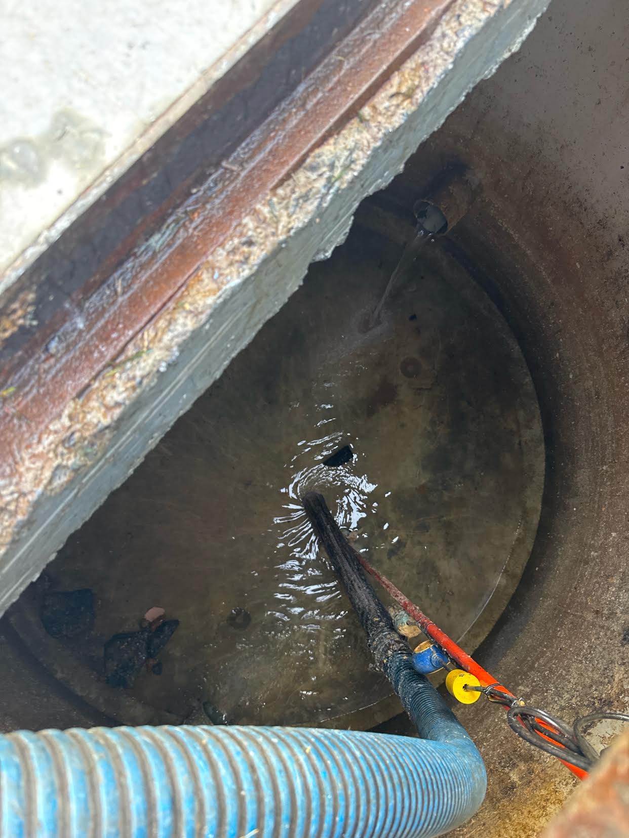 Vacuum hose and cleaning wand inside a holding-tank pump well