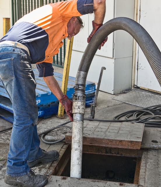 Pump-It operator guiding a vacuum hose into a collection pit