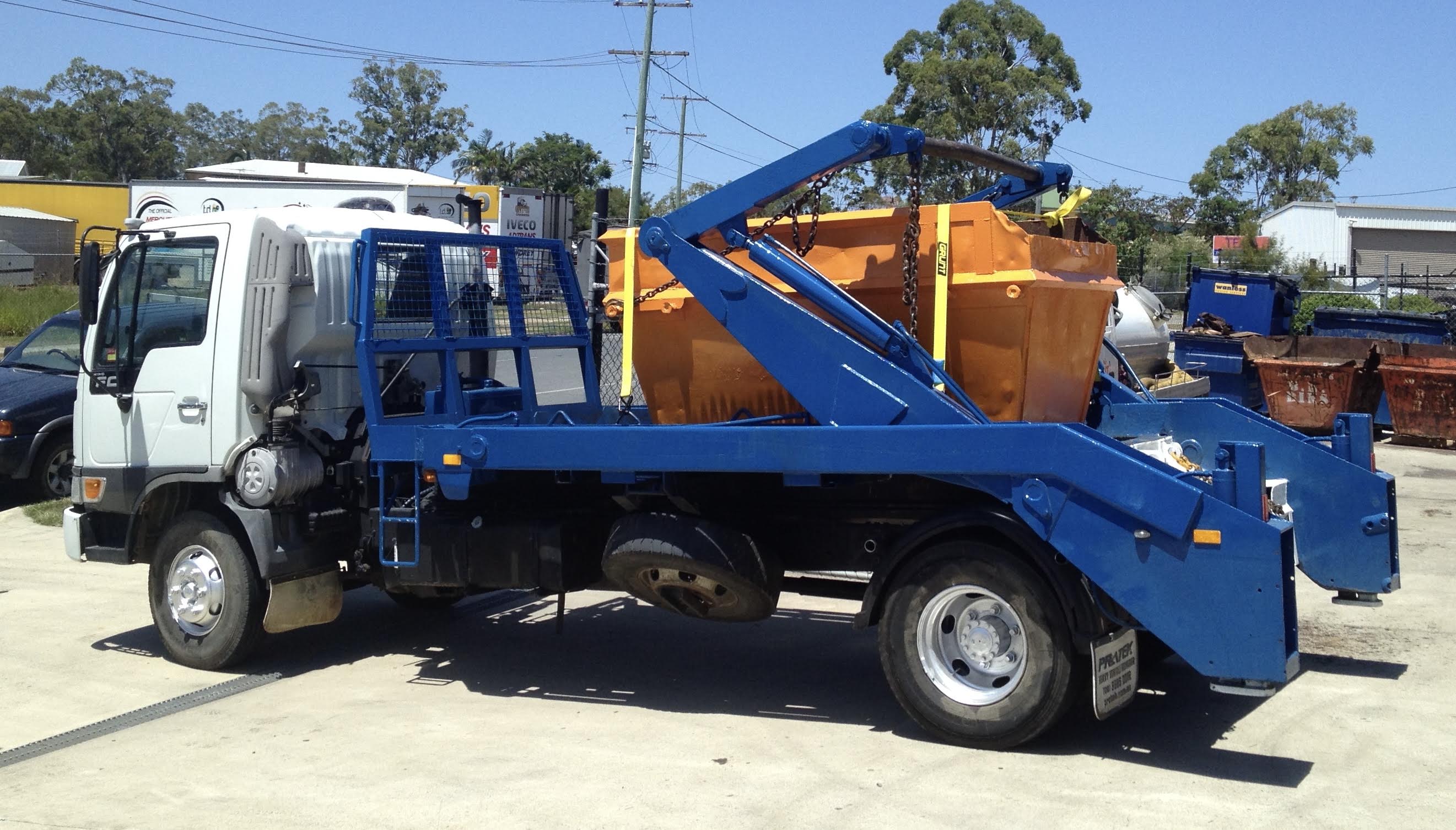 Skip-It delivery truck carrying an orange skip bin