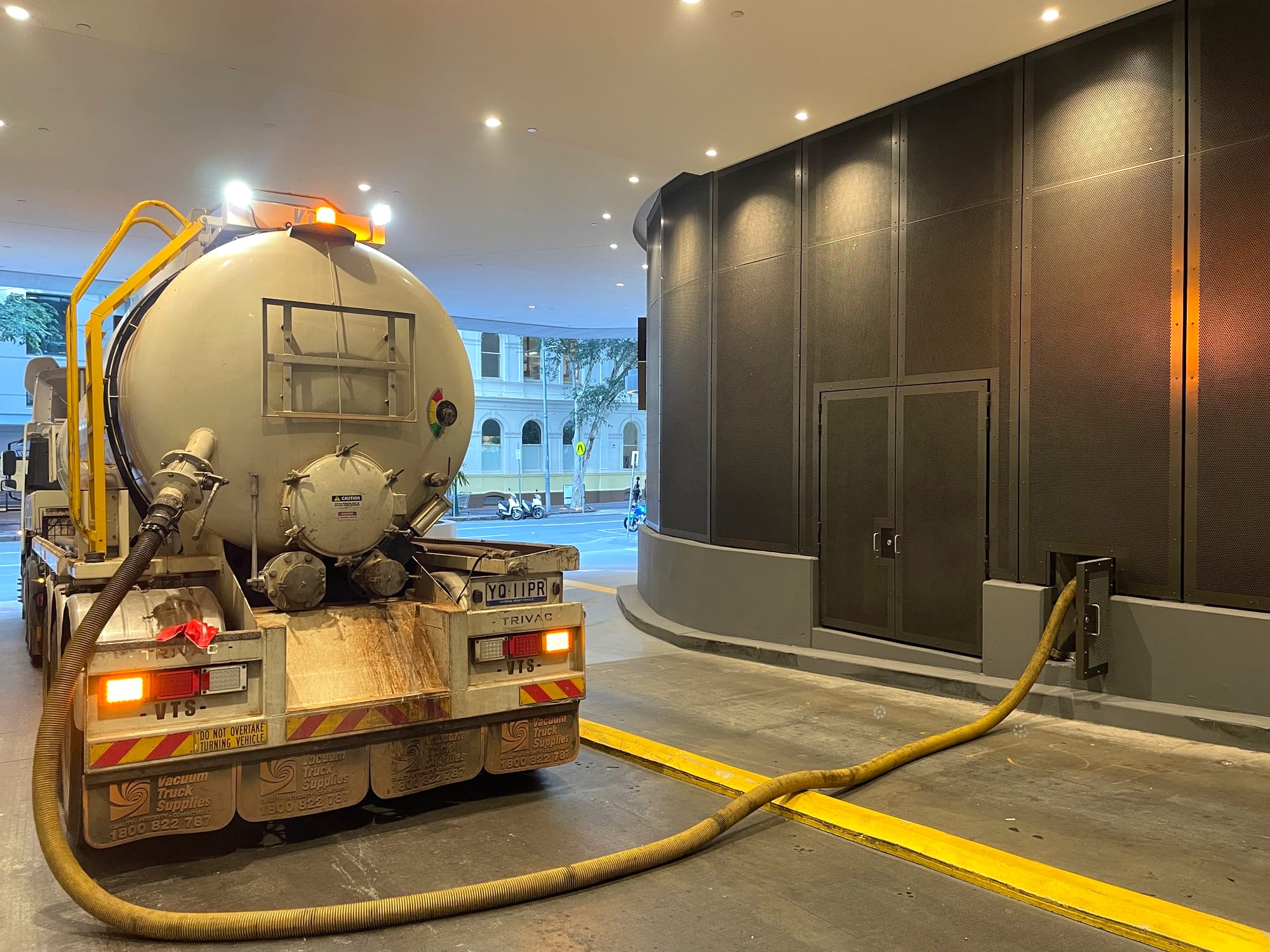Pump-It vacuum tanker working inside a low-clearance basement service bay with the hose connected to the building