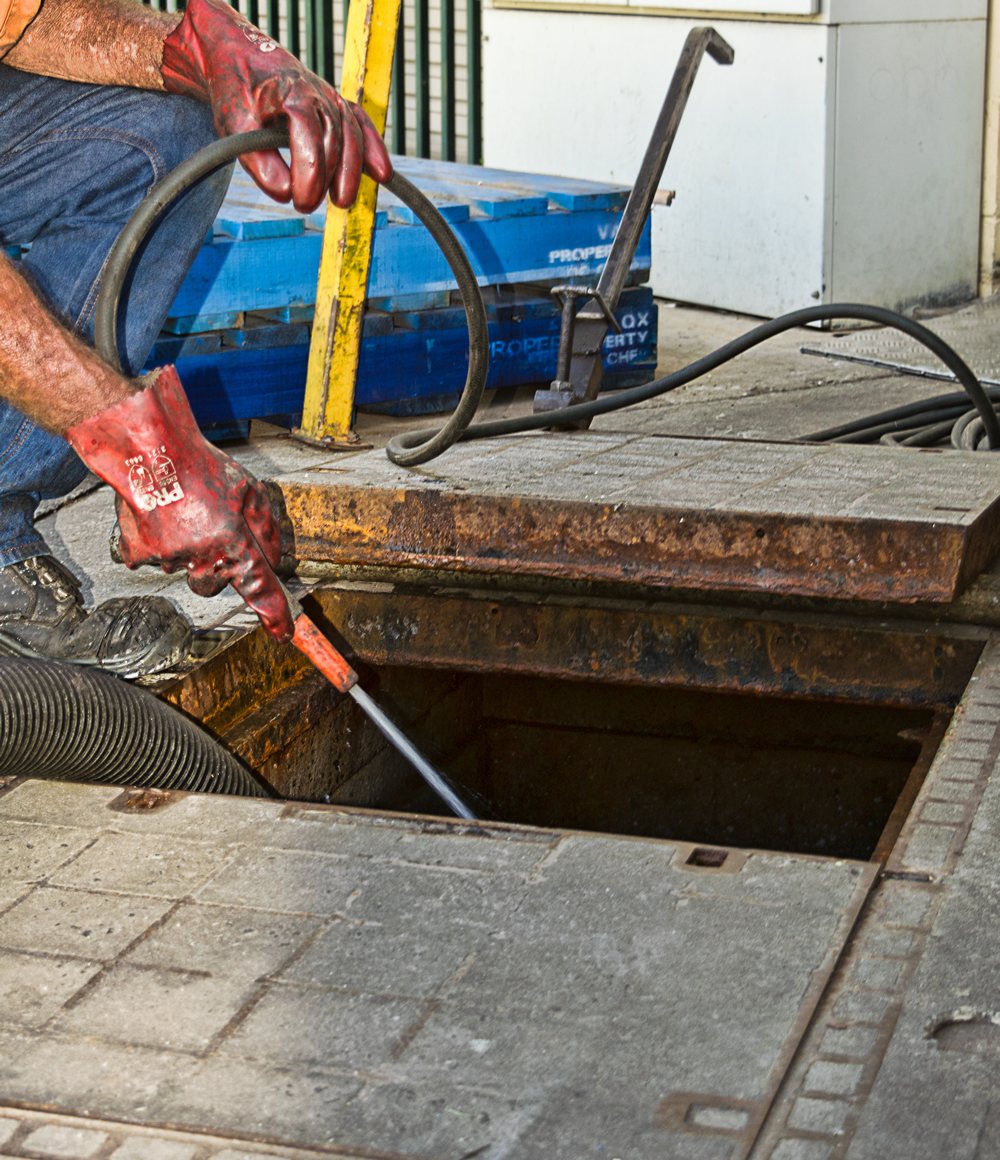 Pump-It operator servicing a grease trap with a vacuum hose
