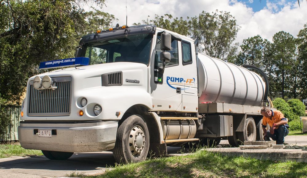 Pump-It operator preparing a vacuum hose at a septic tank